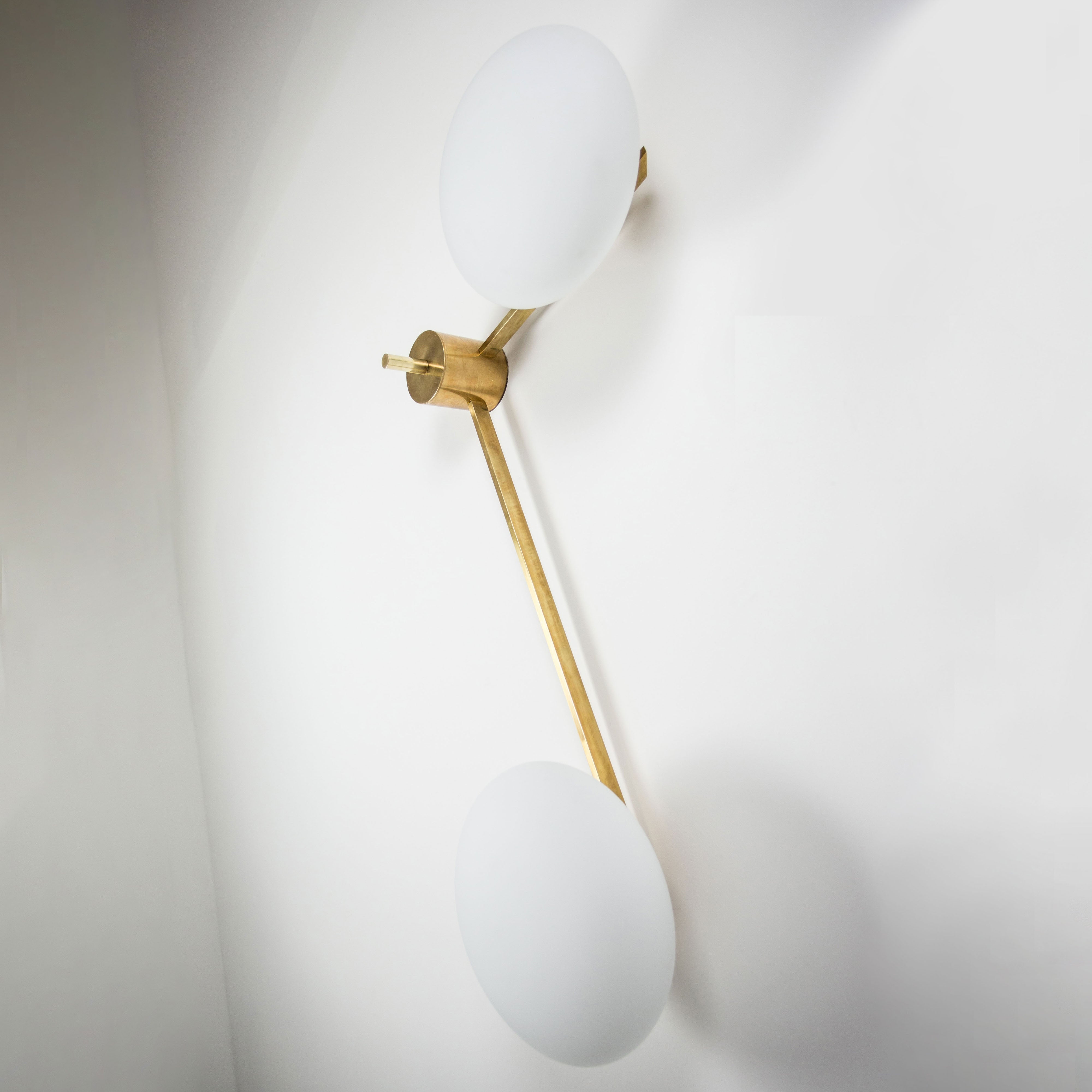 This elegant and iconic lamp in brass and opaline is inspired mid-century Italian design. 12:15 is composed of 2 arms that branch off from a central brass body, supporting with elegant lightness as many Murano opaline glass globes. It can be mounted both as a ceiling and a wall lamp. Angelo Lelli Style