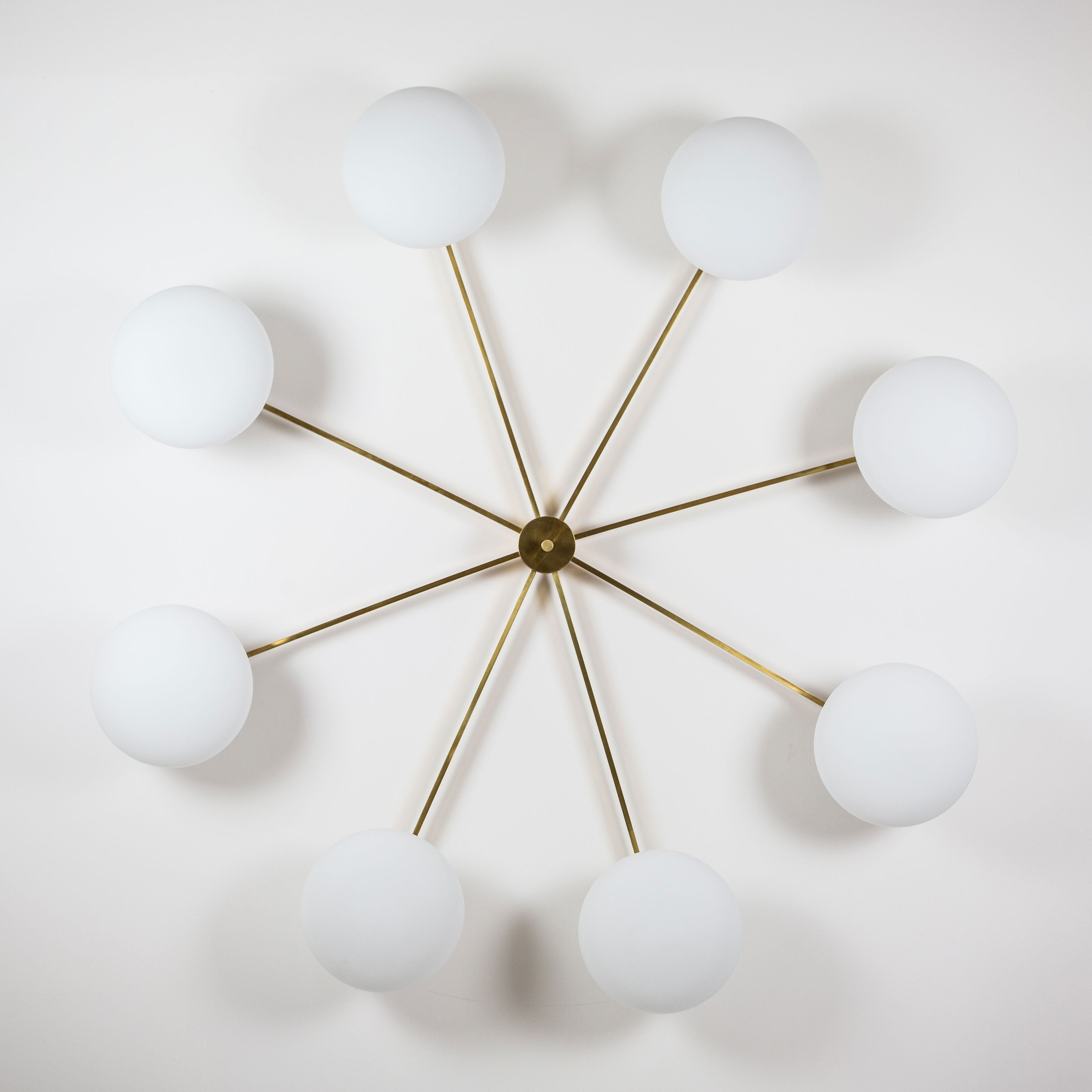 This elegant and iconic lamp in brass and opaline is inspired by mid-century Italian design. Canopy is composed of 8 arms that branch off from a central brass body, supporting with elegant lightness as many Murano opaline glass globes. It can be mounted both as a ceiling and a wall lamp. Angelo Lelli Style