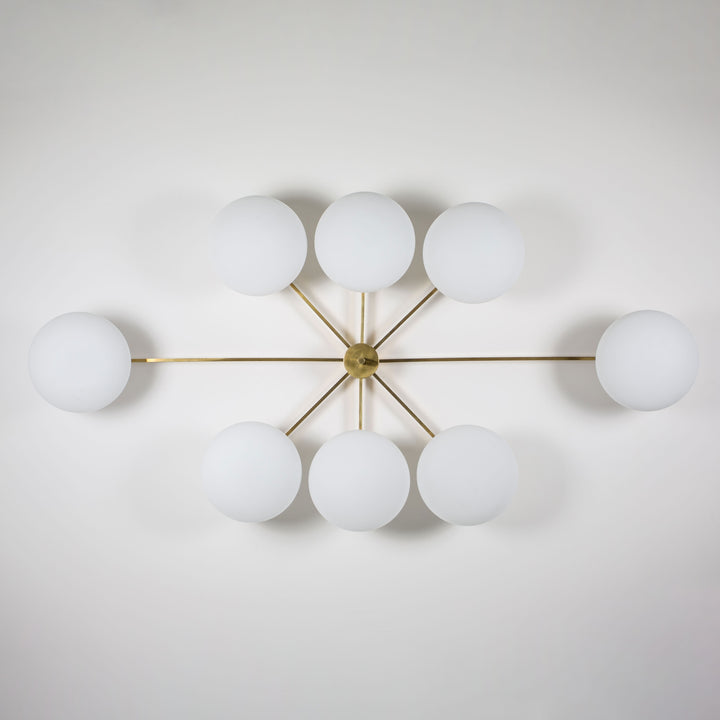 This elegant and iconic lamp in brass and opaline is inspired by mid-century Italian design. Evening is composed of 8 arms that branch off from a central brass body, supporting with elegant lightness as many Murano opaline glass globes. It can be mounted both as a ceiling and a wall lamp. Angelo Lelli Style