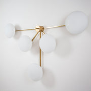 This elegant and iconic lamp in brass and opaline is inspired by mid-century Italian design. Fan is composed of 5 arms that branch off from a central brass body, supporting with elegant lightness as many Murano opaline glass globes. It can be mounted both as a ceiling and a wall lamp. Angelo Lelli Style