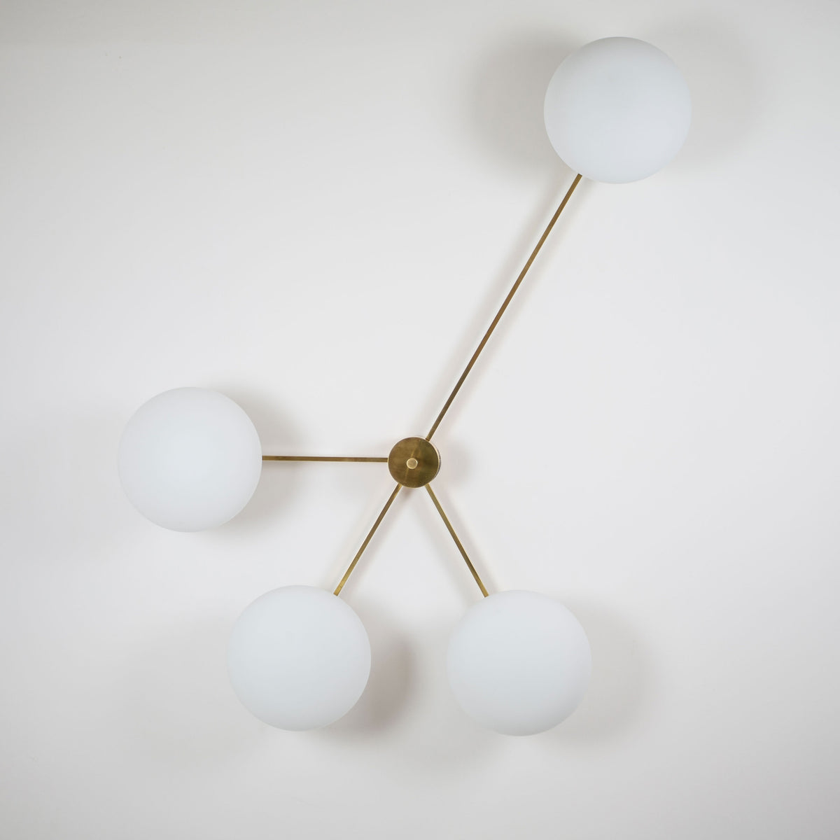 This elegant and iconic lamp in brass and opaline is inspired by mid-century Italian design. Love is composed of 4 arms that branch off from a central brass body, supporting with elegant lightness as many Murano opaline glass globes. It can be mounted both as a ceiling and a wall lamp. Angelo Lilli Style