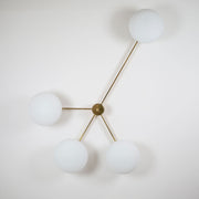 This elegant and iconic lamp in brass and opaline is inspired by mid-century Italian design. Love is composed of 4 arms that branch off from a central brass body, supporting with elegant lightness as many Murano opaline glass globes. It can be mounted both as a ceiling and a wall lamp. Angelo Lilli Style