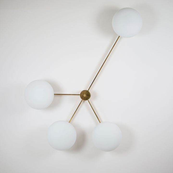 This elegant and iconic lamp in brass and opaline is inspired by mid-century Italian design. Love is composed of 4 arms that branch off from a central brass body, supporting with elegant lightness as many Murano opaline glass globes. It can be mounted both as a ceiling and a wall lamp. Angelo Lilli Style