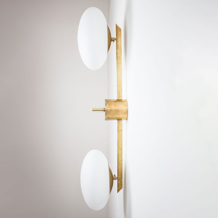 This elegant and iconic lamp in brass and opaline is inspired by mid-century Italian design. Toi&Moi is composed of 2 arms that branch off from a central brass body, supporting with elegant lightness as many Murano opaline glass globes. It can be mounted both as a ceiling and a wall lamp. Angelo Lelli style