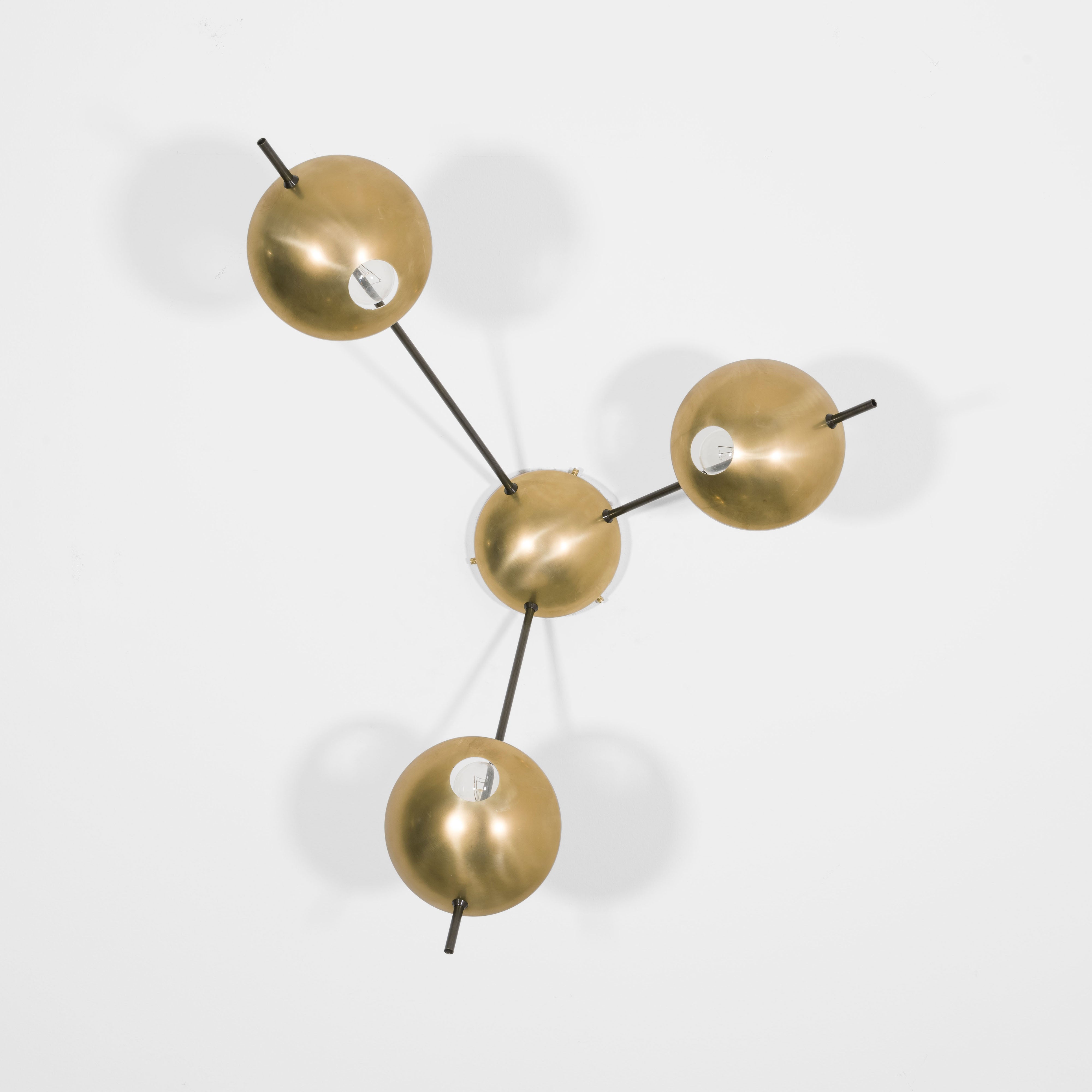 Tribus II, with its elements and its shapes simplicity and with its light and shadow effects, represents a tribute to sundials, ancient solar clocks. From a brass core, 3 thin arms branch off, lightly supporting 3 painted brass plates. Tribus II becomes a point of light and color in any home interiors, an element of creative and colored decoration.