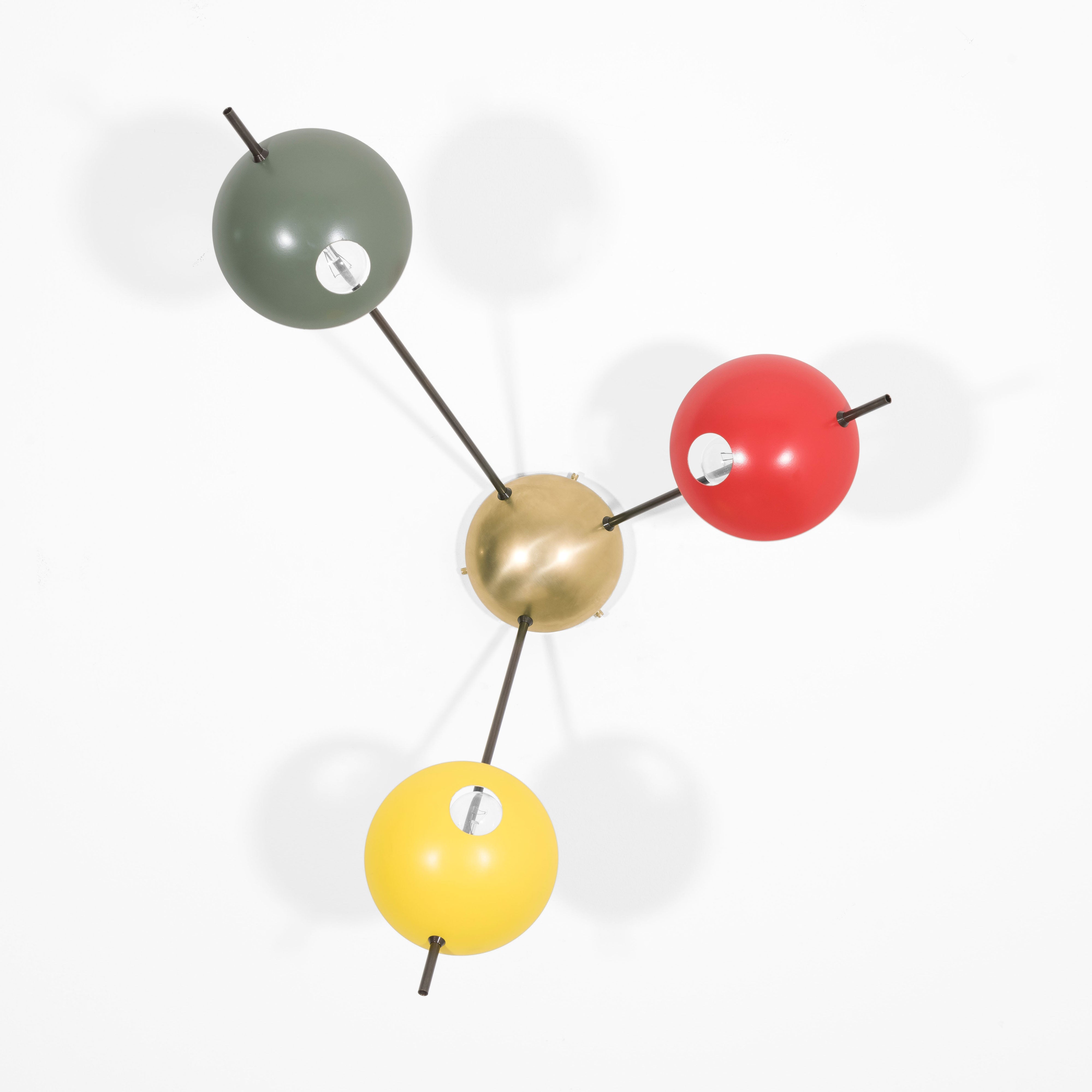 Tribus I, with its elements and its shapes simplicity and with its light and shadow effects, represents a tribute to sundials, ancient solar clocks. From a brass core, 3 thin arms branch off, lightly supporting 3 painted brass plates. Tribus I becomes a point of light and color in any home interiors, an element of creative and colored decoration