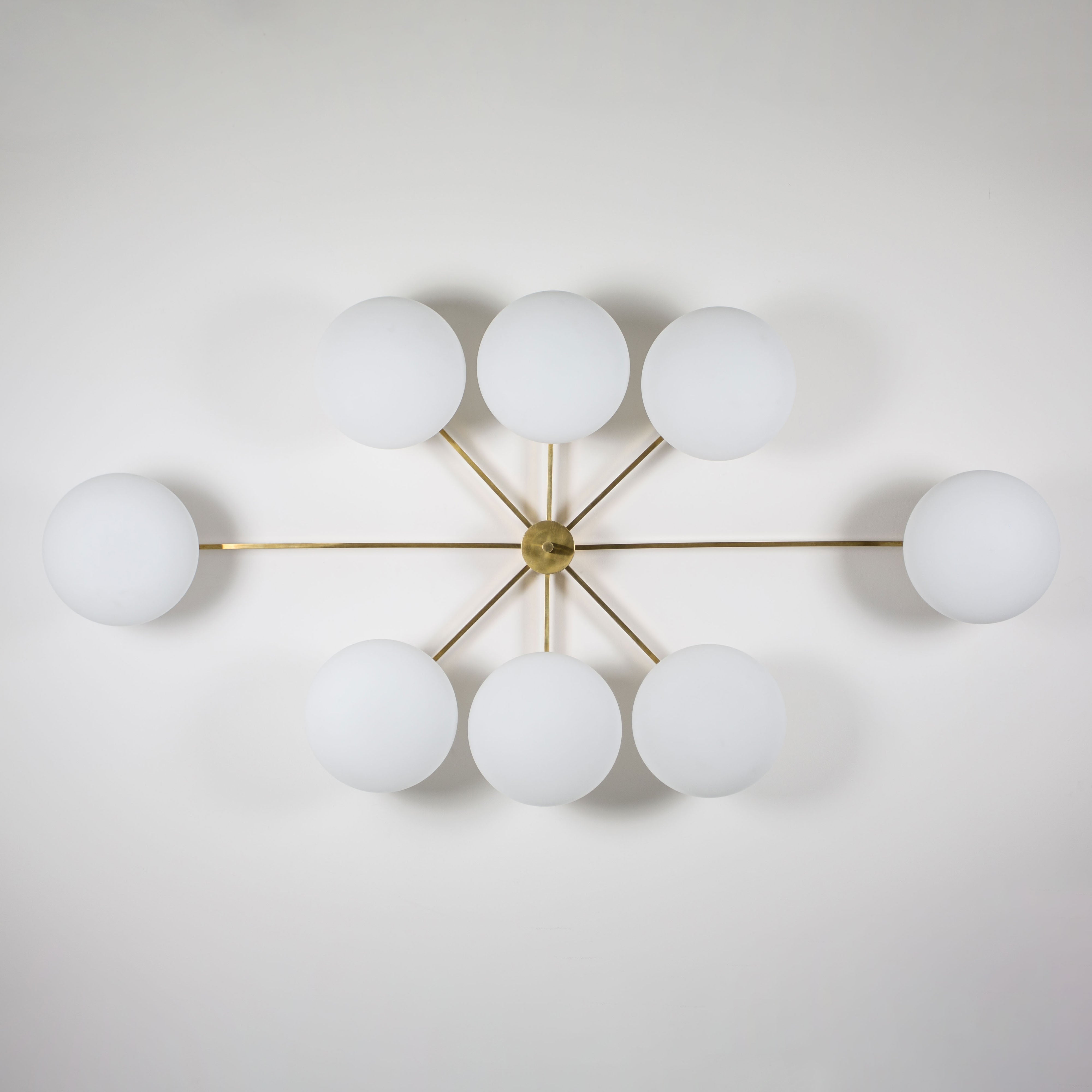 This elegant and iconic lamp in brass and opaline is inspired by mid-century Italian design. Evening is composed of 8 arms that branch off from a central brass body, supporting with elegant lightness as many Murano opaline glass globes. It can be mounted both as a ceiling and a wall lamp. Angelo Lelli Style