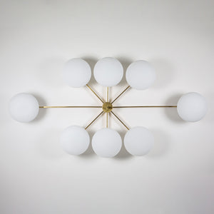 This elegant and iconic lamp in brass and opaline is inspired by mid-century Italian design. Evening is composed of 8 arms that branch off from a central brass body, supporting with elegant lightness as many Murano opaline glass globes. It can be mounted both as a ceiling and a wall lamp. Angelo Lelli Style