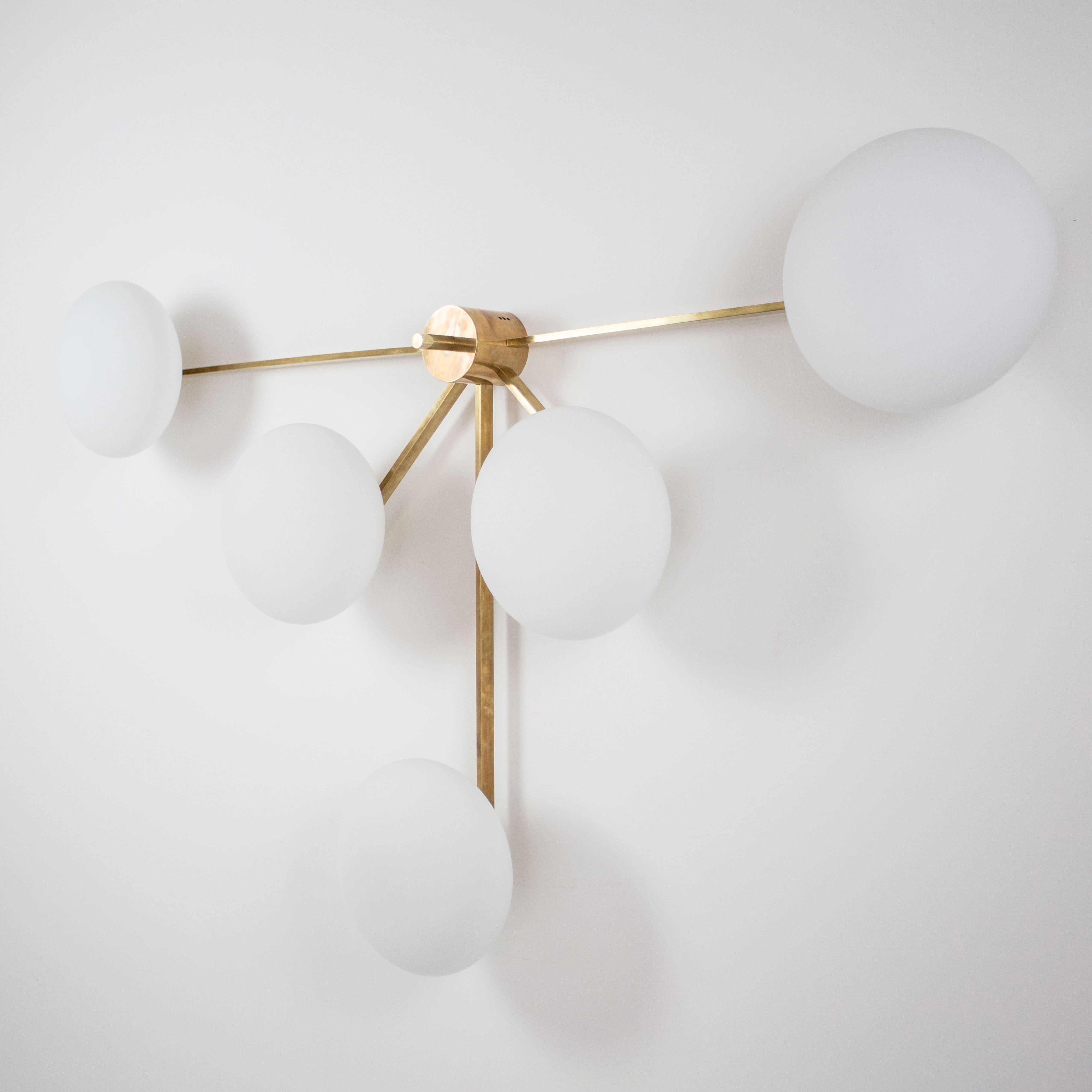 This elegant and iconic lamp in brass and opaline is inspired by mid-century Italian design. Fan is composed of 5 arms that branch off from a central brass body, supporting with elegant lightness as many Murano opaline glass globes. It can be mounted both as a ceiling and a wall lamp. Angelo Lelli Style