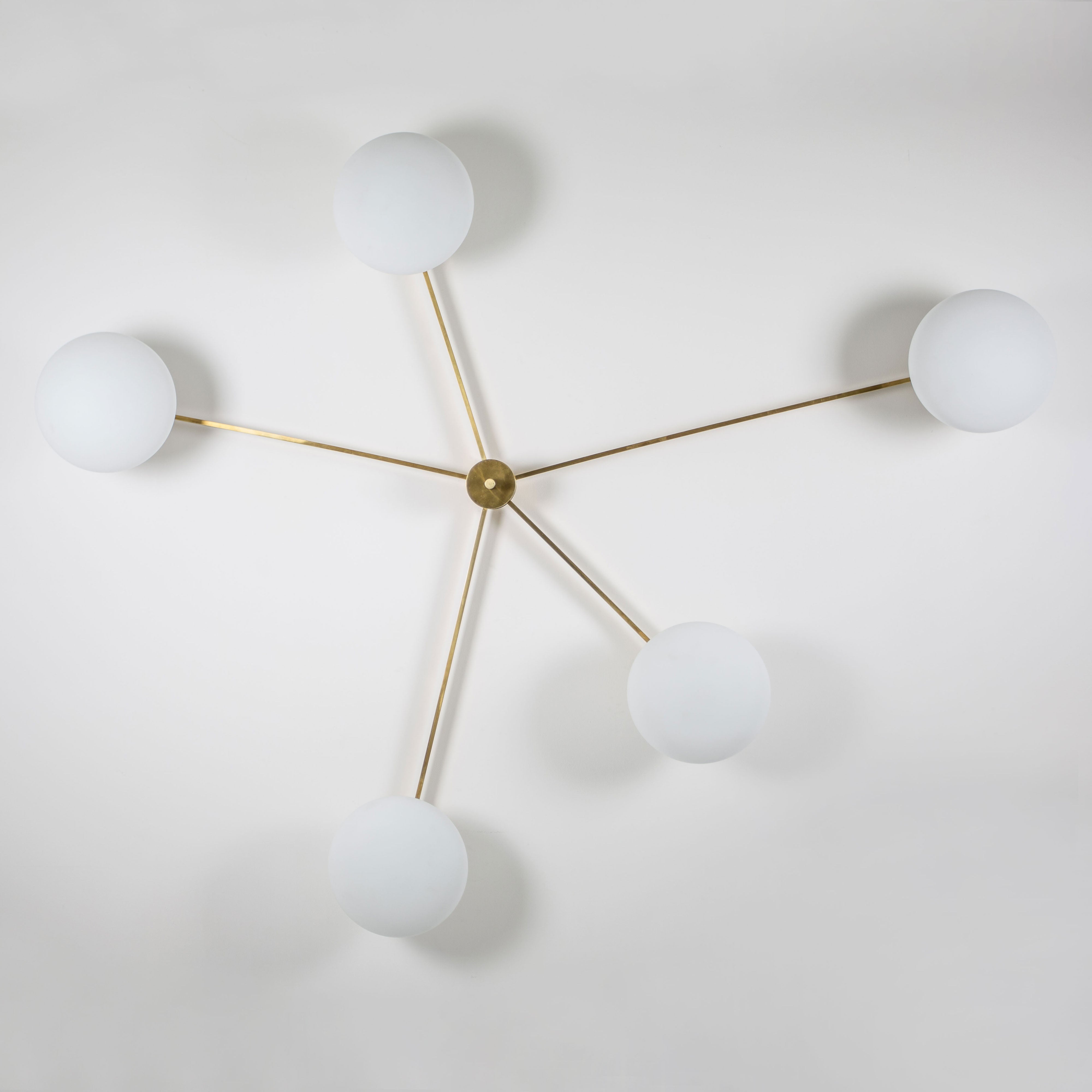 This elegant and iconic lamp in brass and opaline is inspired by mid-century Italian design. Starfish is composed of 5 arms that branch off from a central brass body, supporting with elegant lightness as many Murano opaline glass globes. It can be mounted both as a ceiling and a wall lamp. Angelo Lilli style